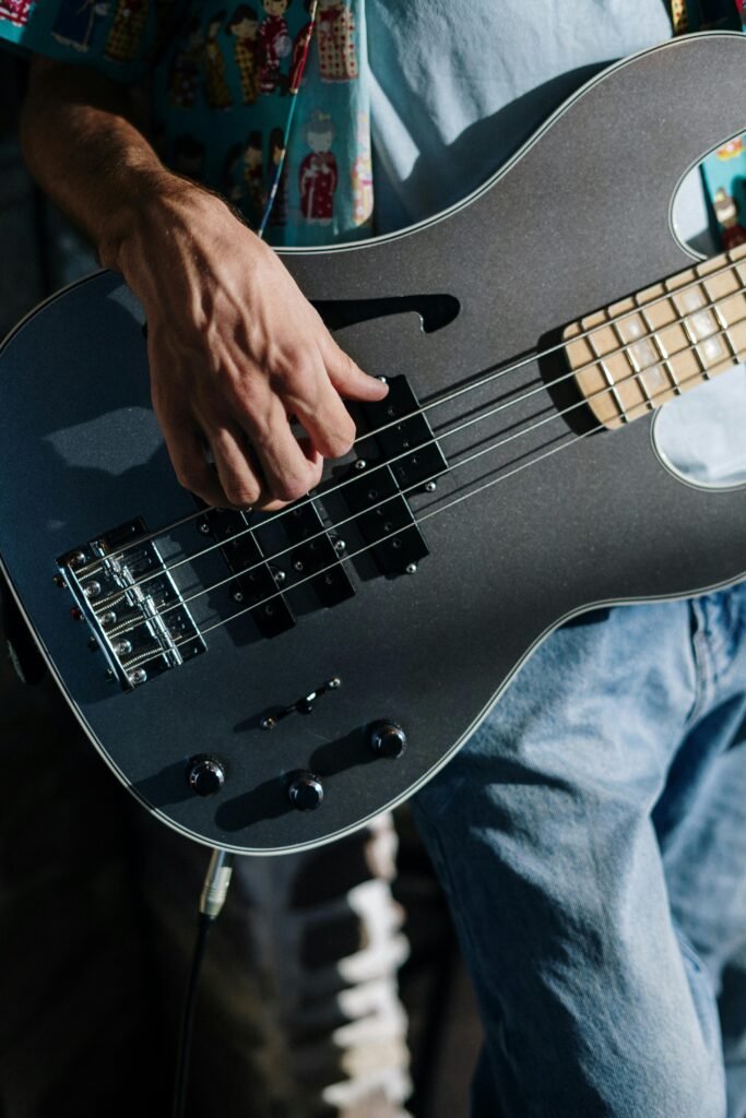 oil-1 Musician performing with a sleek electric bass guitar in a home studio setting.