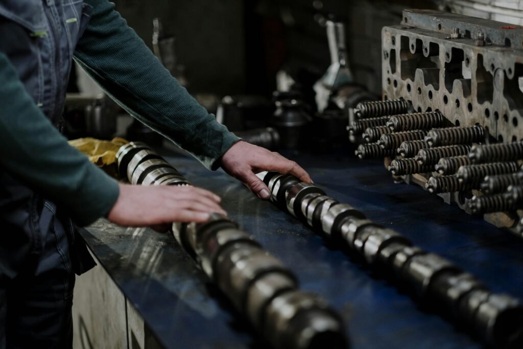 oil-1 Worker handling camshafts and cylinder head in a mechanic workshop.